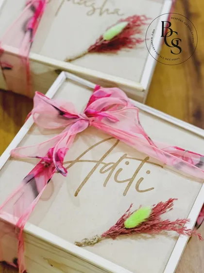A close-up of the personalized wooden box for a bridesmaid proposal. The elegant script of the name 'Aditi' and the delicate floral and ribbon details make it a cherished keepsake box.