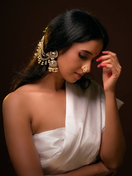 A beautiful and serene ethnic portrait. The model's traditional jewelry and gentle expression are highlighted by warm, soft lighting.