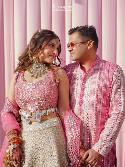 A lovely portrait of the couple against a pink backdrop at their Haldi ceremony. Their coordinated outfits and happy smiles say it all.