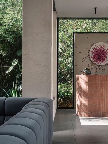 The entertainment room features a comfortable, large sofa and a bar made of pink bricks. The custom artwork behind the bar adds a whimsical touch to this relaxed, social space.