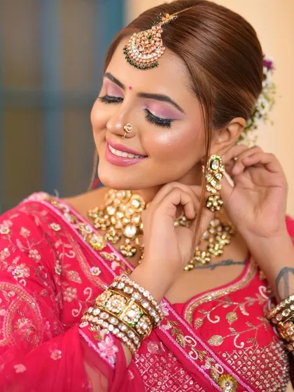 A bride getting ready, adjusting her Kundan earring. This candid shot captures the beauty of the jewellery and the intimate moments before the wedding.