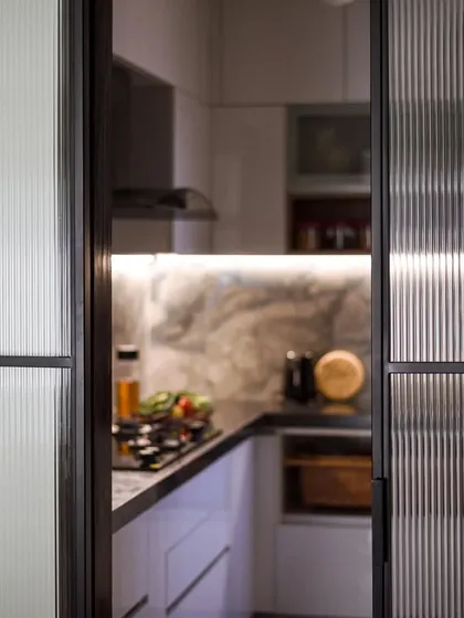 The kitchen is separated from the dining area by a sliding door with fluted glass panels. This allows for privacy while still letting light pass through.