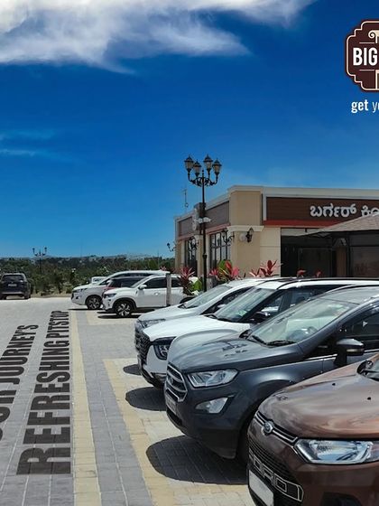 A shot of our full parking lot on a sunny day, with the text "Your Journey's Refreshing Pitstop" projected on the ground, showing our popularity.