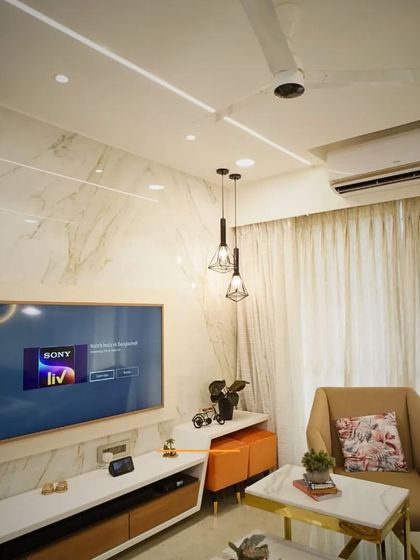 This view highlights the TV unit, designed with a marble-finish backdrop and sleek wooden paneling. We focus on creating entertainment spaces that are stylish and clutter-free.