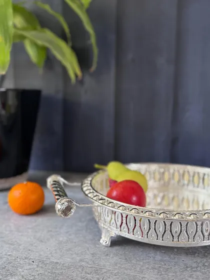 This round silver tray features open lattice sides, a mirrored bottom, and decorative metal handles. It is perfect for serving drinks or snacks with a stylish touch.