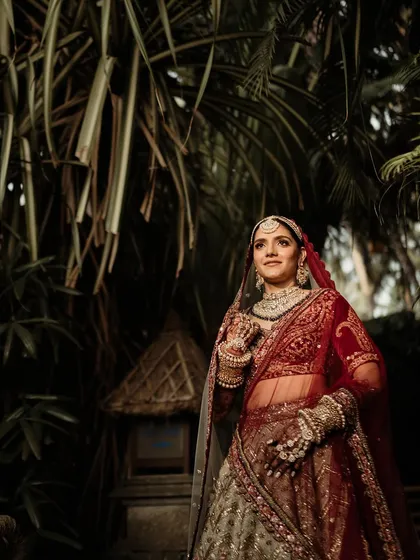 A classic bridal portrait, showcasing her regal attire and confident poise against a backdrop of tropical foliage.