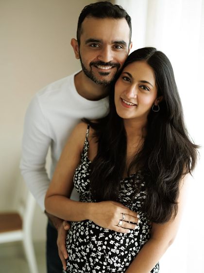 A classic portrait of a smiling, happy couple. His arms are wrapped around her, both looking at the camera, sharing their joy with the world.