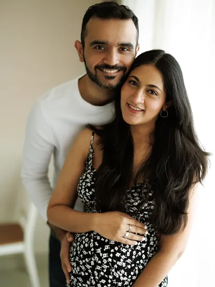 A classic portrait of a smiling, happy couple. His arms are wrapped around her, both looking at the camera, sharing their joy with the world.