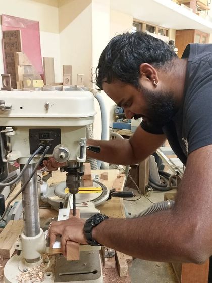 Tejus using the drill press to remove the bulk of the waste from a mortise. This is much faster than chopping it all out with a chisel.
