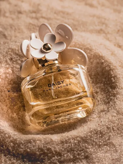 A classic perfume bottle shot in soft, warm light on a bed of fine sand. This simple yet elegant setup highlights the bottle's design and creates a feeling of timeless luxury.