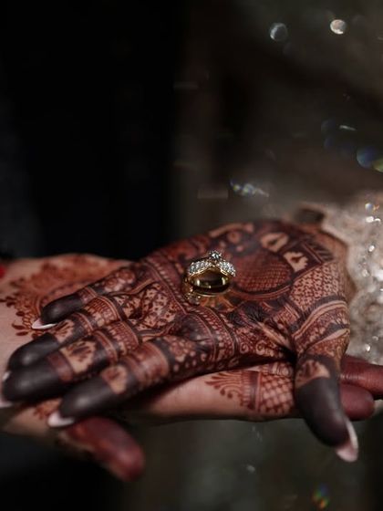 A close-up of the engagement ring against the deep maroon stain of the bridal mehendi, showing the beautiful contrast.