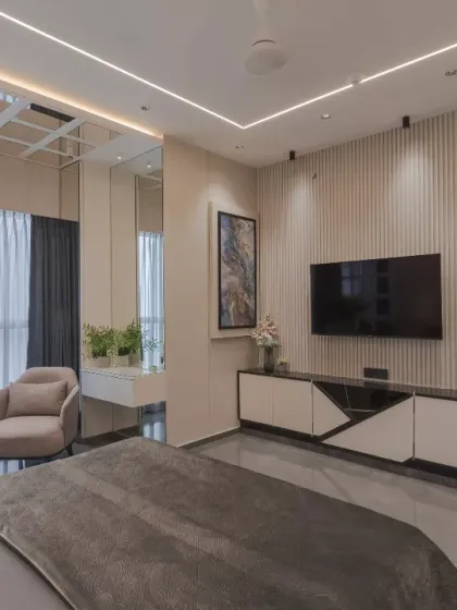 This bedroom space exudes modern elegance with its bespoke design. The fabric paneling, accentuated by gold trims, creates a rich backdrop for the floating console and sleek TV unit, optimizing vertical space.