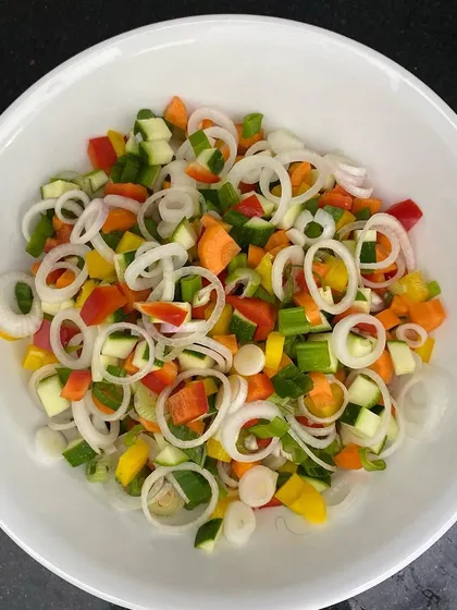 Another view of my salad preparation. The mix of colorful vegetables like red, yellow, and green peppers with onion rings makes for a visually appealing and healthy base.