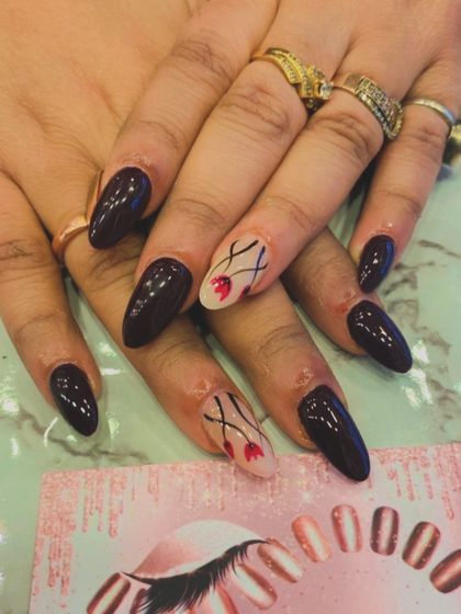 A sophisticated and artistic set of long, almond-shaped nails. The deep maroon polish is paired with accent nails that have a sheer base and delicate, hand-painted red flowers.