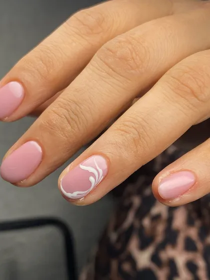 This gel manicure looks just like a Russian manicure because of the careful prep. A soft pink set with a white swirl accent.