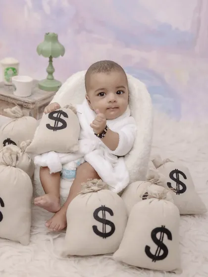 This little boss is ready to take on the world. A fun and creative "boss baby" theme with a bathrobe and bags of money shows off a playful and confident side.