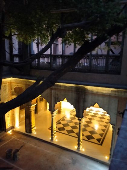 The courtyard at night, with atmospheric lighting highlighting the restored arches and the new black-and-white flooring, creating a magical ambiance for evening events.