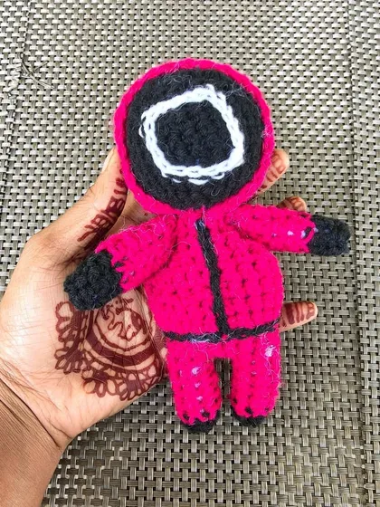 Holding my handmade Squid Game guard amigurumi. The size is perfect for a collectible or a keychain.