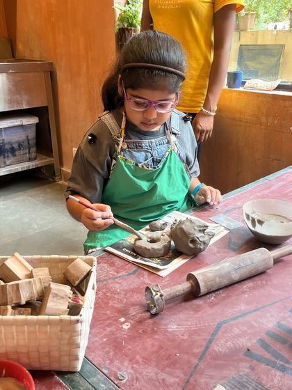 This little one is completely focused on painting her clay creation. Our summer pottery camp includes both shaping and decorating, allowing kids to see their project through from start to finish.