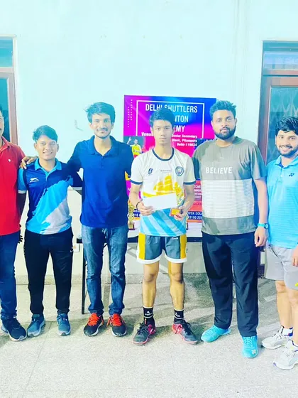 A tournament winner stands with our team of NIS certified coaches. This photo represents the collaborative effort behind every victory at our academy.