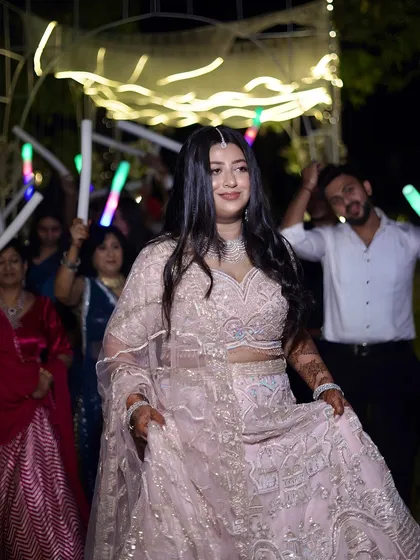 The bride makes her entrance at the Sangeet, with guests holding light sticks, creating a fun, party-like atmosphere.