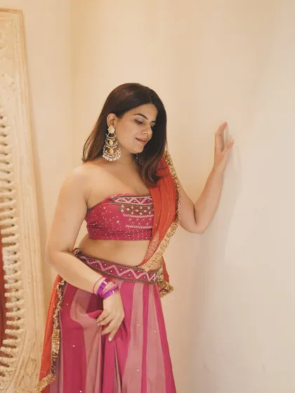 A graceful pose showcasing a beautiful bandhani-style blouse and a striped lehenga. This is a great outfit inspiration for a modern traditional look.