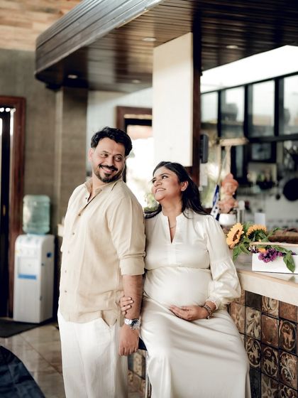 A happy indoor shot of the couple in a rustic kitchen space, holding hands and sharing a look of love.