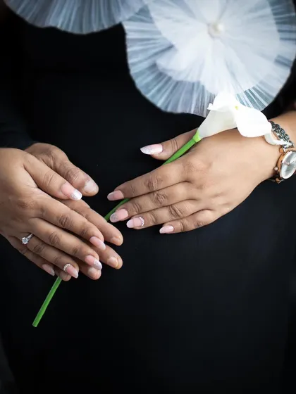 Focusing on the details. This close-up shot shows the mother's hands gently holding a lily over her baby bump, a simple and beautiful symbol of new life.