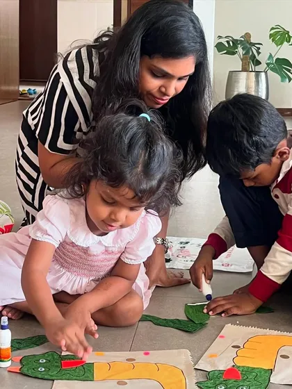 A mother helping her children with their dragon paper bag puppets. Craft time is a wonderful opportunity for family bonding.