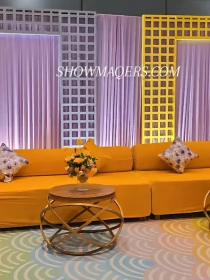 A comfortable and stylish lounge area for a Haldi event, with bright yellow sofas and modern white lattice backdrops.