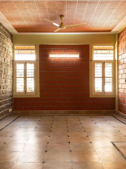 An empty room showcasing the material palette: exposed stone and brick walls, a clay tile filler ceiling, and patterned floor tiles.