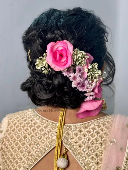 A lush, floral bridal bun for a Gujarati bride. The combination of different pink flowers creates a beautiful texture and adds a romantic touch to the overall look.