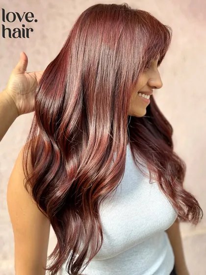 The happy client reveal of her cherry-cola transformation. She's smiling, and her hair looks absolutely incredible.