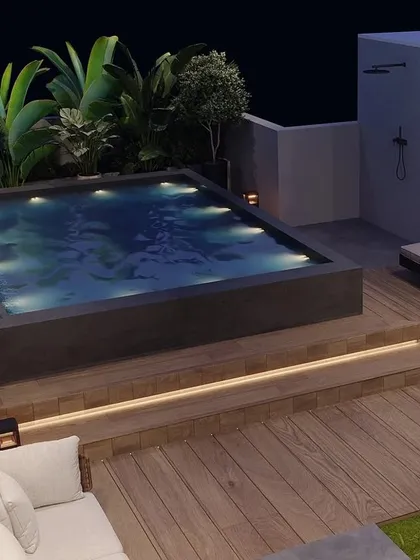 We transformed this Gurugram rooftop into a private oasis with a custom-built pool. The design features warm, integrated lighting under the steps, comfortable lounge chairs, and lush tropical plantscaping to create a resort-like feel right at home.
