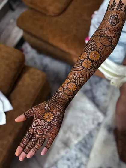 A single-arm view of Saba's mehendi, showing the initial 'S' on the back of her hand.