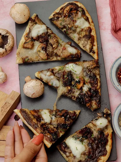 A mushroom flatbread styled with a pink background for a Valentine's Day menu.