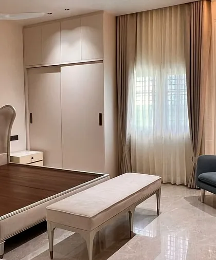 A serene bedroom setting from a project with Aura Designgram. We crafted the upholstered bed with its elegant curved headboard, the matching bench, and the sleek armchair to create a cohesive and calming personal sanctuary.