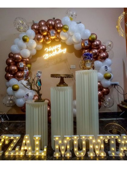 We personalize your celebration with light-up marquee letters for a truly custom touch. This beautiful rose gold and white balloon arch is the perfect frame for the birthday person's name, set against a simple wall for a clean, sophisticated look.