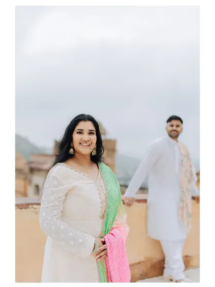 A bright and happy portrait of the bride, with the groom slightly out of focus in the background, creating a playful and modern feel.