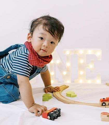 The birthday boy crawling around his train set, happy and engaged. Play-based shoots result in the most natural and joyful photos.