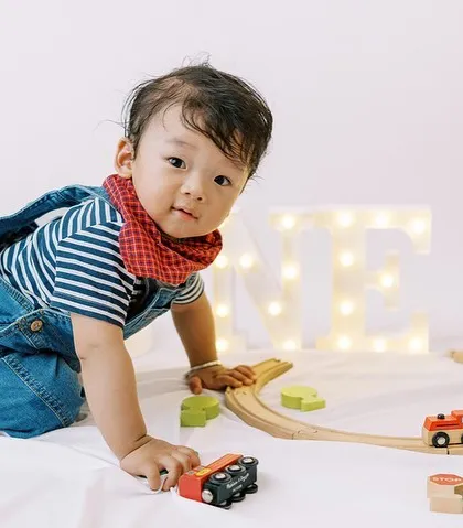 The birthday boy crawling around his train set, happy and engaged. Play-based shoots result in the most natural and joyful photos.