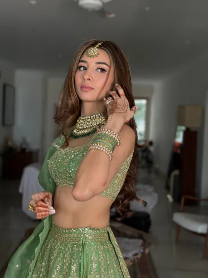A candid moment showing the beautiful details of her jewelry and henna. The makeup is subtle, with a focus on a flawless complexion.