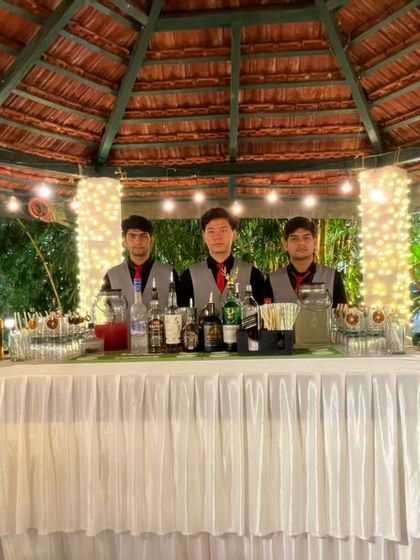We can create a beautiful bar experience in any location, like this charming gazebo setup for an outdoor wedding. The white draped counter and string lights create a romantic and festive atmosphere for the celebration.