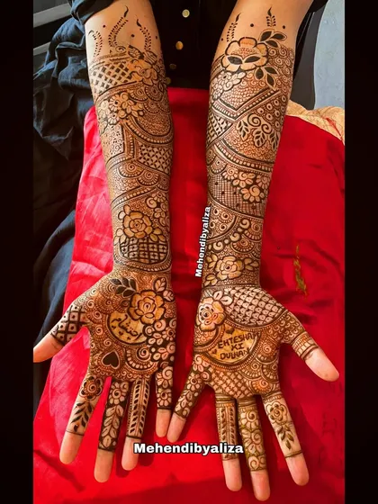 A full bridal henna design with floral patterns and the couple's names. The intricate details cover the hands and arms beautifully.