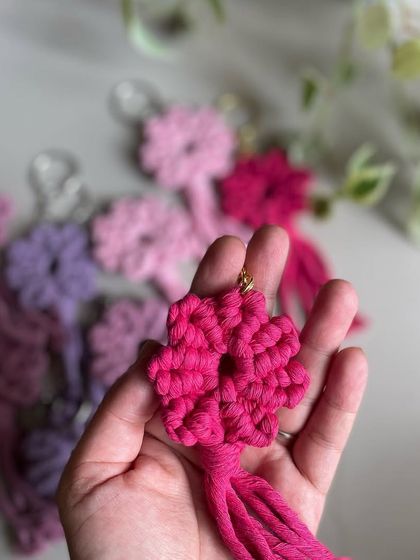 A close-up of my macrame flower keychain in a vibrant pink. It's a lovely, textured design that feels great to hold.