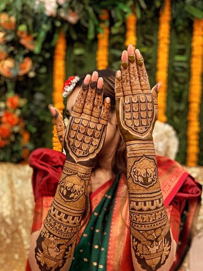 This design features bold, shield-like patterns on the back of the hand, filled with intricate checks and traditional elephant figures on the arms.