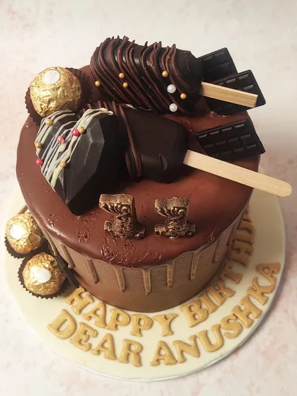 For the ultimate chocolate lover, we created this decadent chocolate drip cake. This masterpiece is lavishly decorated with chocolate-dipped cakesicles, geometric chocolate hearts, and Ferrero Rocher chocolates, all cascading over a rich chocolate ganache drip, promising an unforgettable indulgence.