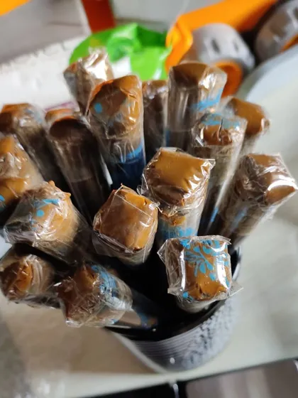 A bundle of freshly filled henna cones, showing the rich paste at the tip. They are wrapped and ready for use.