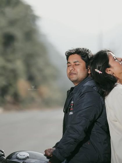 A quiet, serene moment for the couple, resting back-to-back on their bike on a quiet mountain road. It’s a peaceful shot that speaks volumes about their comfort and trust in each other.