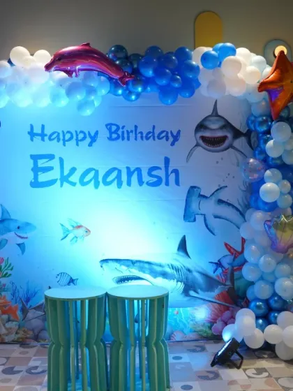 The main stage for an ocean-themed party, with a beautifully lit backdrop of sharks and sea life. It's an adventurous theme for a young explorer.